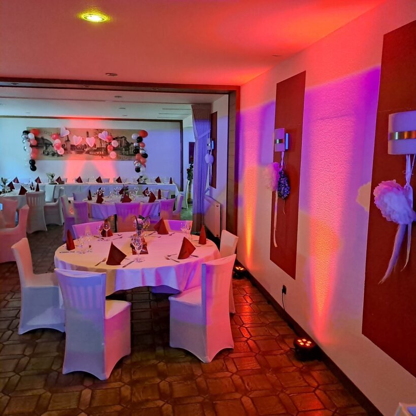 Professioneller DJ-Aufbau in einem Festsaal – stilvolle Beleuchtung, hochwertige Soundanlage und perfekte Atmosphäre für Hochzeiten und Events.