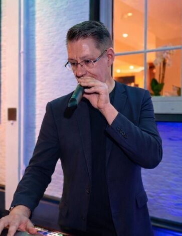 Persönliches Bild von DJ Herford Stefan Masur, wie er aktiv Musik auflegt und die Party professionell moderiert