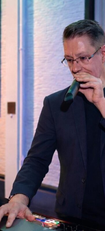 Persönliches Bild von DJ Herford Stefan Masur, wie er aktiv Musik auflegt und die Party professionell moderiert